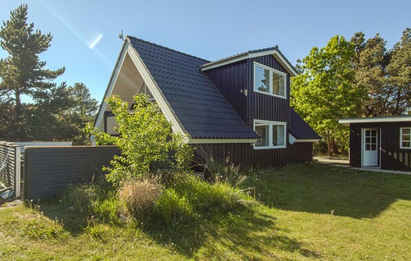 A two-story house with a dark roof, a visible attic window, and a small attached garage. - 4 bedroom lovely home in Glesborg (Glesborg)