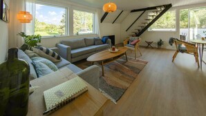 A spacious living room with a sofa, a coffee table, and a staircase. - 4 bedroom lovely home in Glesborg (Glesborg)
