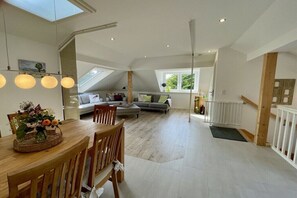 Ein geräumiger Loft mit Essbereich, einem Wohnzimmer mit Sofa und Blick ins Freie.