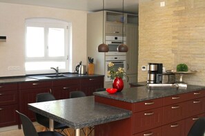 Eine moderne Küche mit dunklen Schränken, einer Granit-Arbeitsplatte, einer roten Vase und einer Kaffeemaschine.