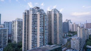 Un edificio residencial alto con varios balcones, rodeado de otros edificios altos.