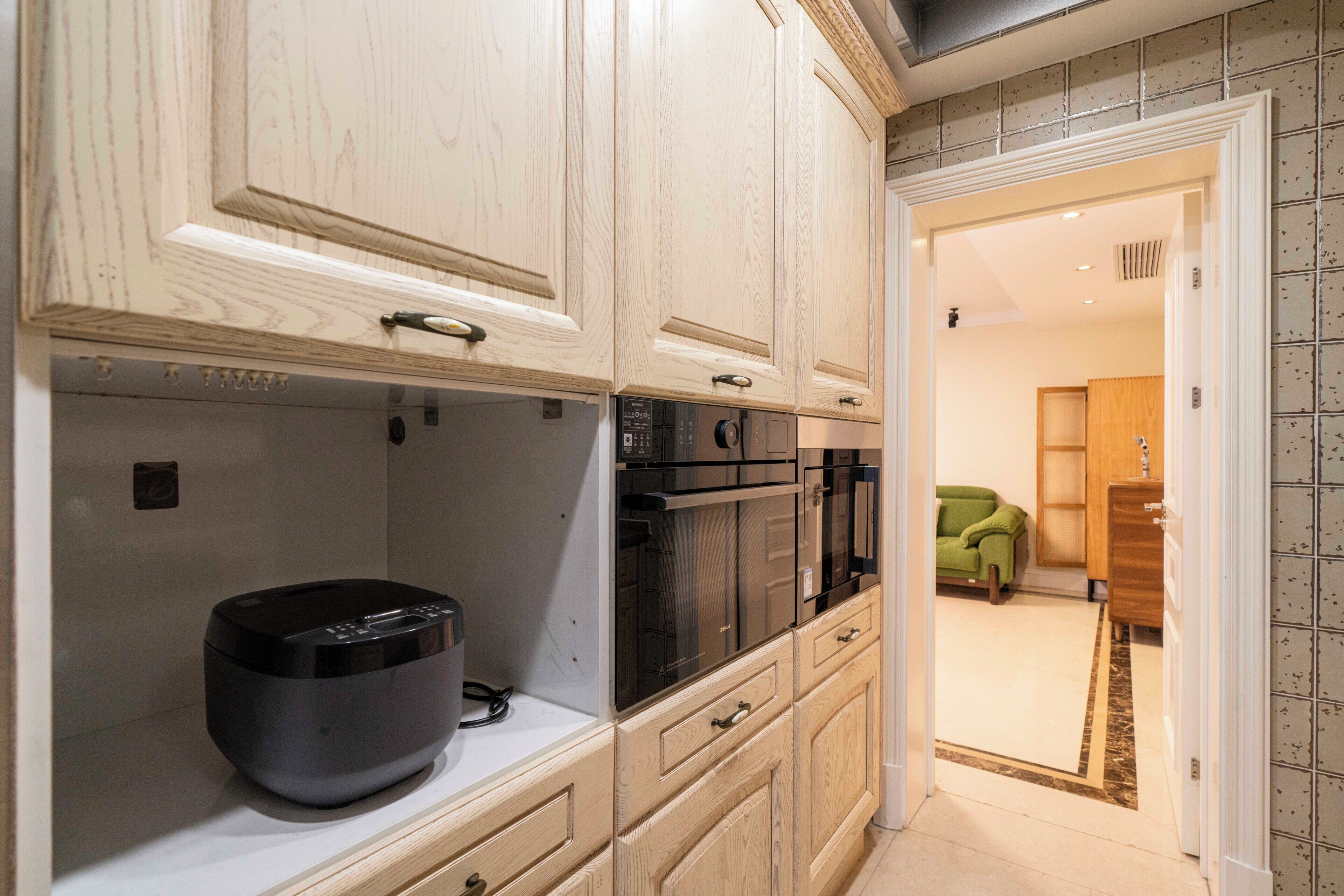 A kitchen with wooden cabinets, a built-in oven, and a coffee machine.