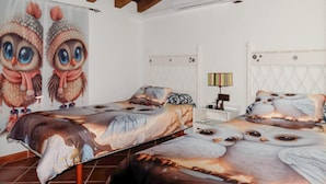 Quarto com duas camas, cada uma com roupa de cama com tema de coruja, mesa de cabeceira com abajur e parede com arte de corujas.