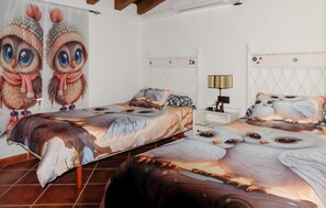 Ein Schlafzimmer mit zwei Betten, beide mit Eulen-Motiv, einem Nachttisch mit Lampe und einer Wand mit Eulenbildern.