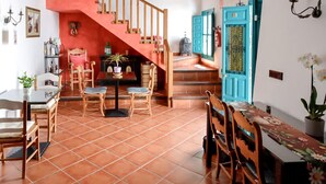Uma sala de jantar com uma mesa, cadeiras, uma escada e uma porta azul.