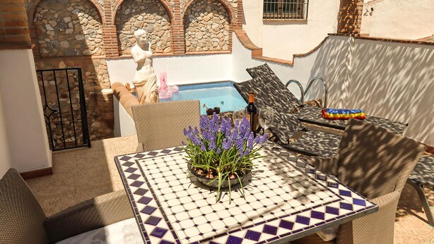 Um pátio com piscina, móveis de exterior e uma estátua.