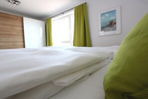 Ein Hotelzimmer mit Bett, einem fensterbepften Fenster und einem gerahmten Bild an der Wand.