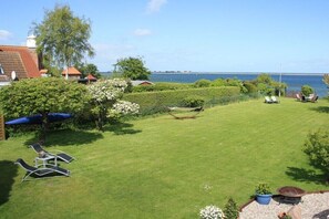 Ein gepflegter Rasen mit Liegest ühlen, einer Hängematte und Blick aufs Meer.