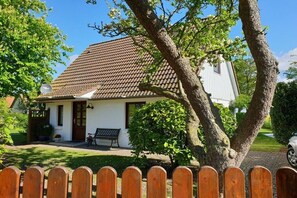Ein eingeschossiges Gebäude mit braunen Ziegeln, einer weißen Fassade und einer Veranda mit einer Bank.