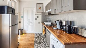 Eine kompakte Küche mit Kühlschrank, Waschmaschine und Kaffeemaschine.
