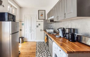 Eine kompakte Küche mit Kühlschrank, Waschmaschine und Kaffeemaschine.