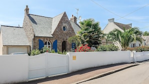 Ein Steinhaus mit weißem Zaun, einer Garage und einer Auffahrt.