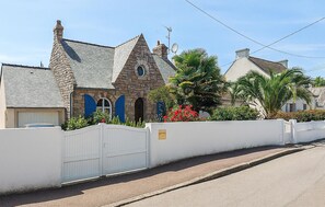 Ein Steinhaus mit weißem Zaun, einer Garage und einer Auffahrt.