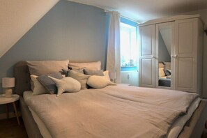 A bedroom with a bed, nightstand, and wardrobe. - Holiday apartment with 2 bedrooms (Sankt Peter-Ording)