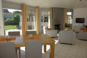 Ein modernes Wohnzimmer mit Kamin, Essbereich und Wand-Fernseher.