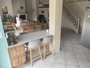 Ein Essbereich mit einem langen Tisch, Stühlen, einer Kaffeemaschine und einem Fernseher.