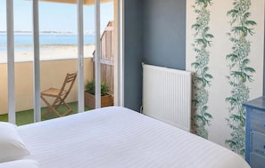 A bedroom with a bed, a chair, a radiator, and a view of the beach. - 1 bedroom beautiful apartment in La Rochelle (La Rochelle)