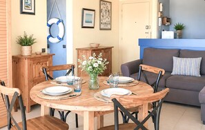 A dining area with a wooden table, chairs, and a vase of flowers. - 1 bedroom beautiful apartment in La Rochelle (La Rochelle)