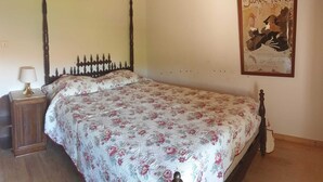 Un dormitorio con cama, mesita de noche, lámpara de pared y un cartel.