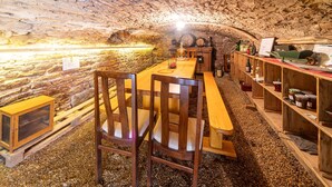 Ein unterirdischer Essbereich mit Holztischen, Steinwänden und rustikalem Ambiente.