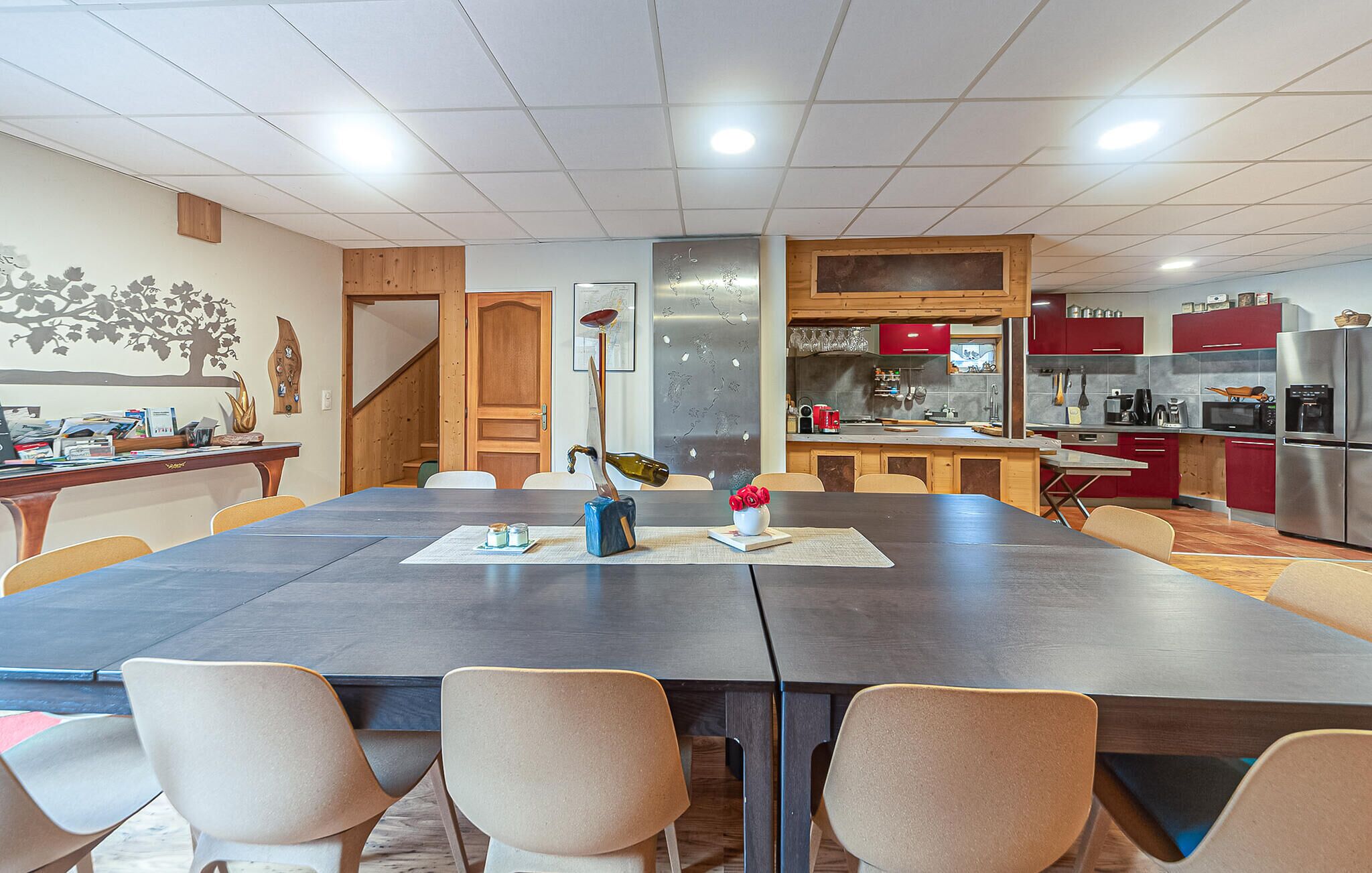 A modern kitchen with a dining area, wooden accents, and a stainless steel refrigerator.