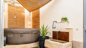 Een wellnessruimte met een jacuzzi, een potplant, een waterfontein van steen en een gestructureerde muur.