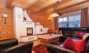 Ein gem ütliches Blockhaus-Interieur mit Kamin, Ledersitzmöbeln und einem Holztisch.