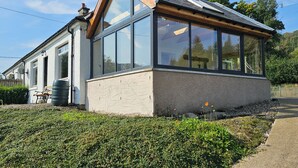 A modern building with large windows, a sloped roof, and a bell on the roof. - Cosy Cottage close to Munros and cycle route (Lochearnhead)