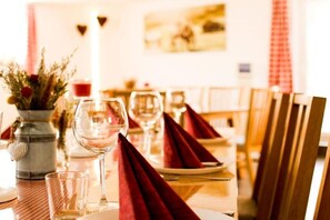 A dining table with red napkins, a glass of water, and a vase with flowers. - Holiday home in Hayingen with barbecue (Hayingen)
