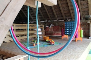 A wooden playroom with a sloped ceiling, a wooden playpen, and colorful toys. - Holiday home in Hayingen with barbecue (Hayingen)