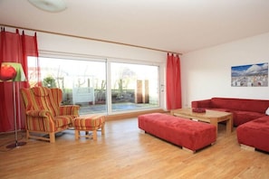 Ein Wohnzimmer mit Sofa, Sessel, Hocker und Tisch.