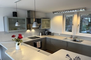 A modern kitchen with a built-in oven, a sink, and a window with a view of the outdoors. - Holiday home with 2 bedrooms (Herrsching)