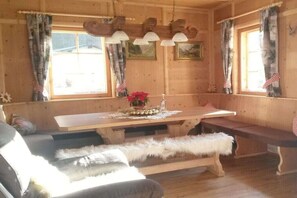 Ein Holzblockhaus-Interieur mit Esstisch, Bänken und einer Couch.