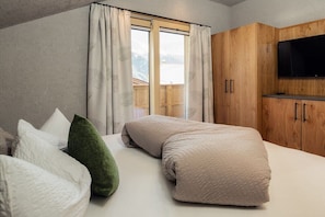 Ein Schlafzimmer mit einem Bett, Kissen, einem Holzschrank und einem Fernseher.