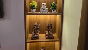 A wooden cabinet with shelves containing decorative items and a remote control on the floor. - The Bunny House Homestay (Mussoorie)