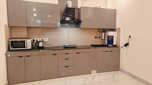A kitchen with a microwave, kettle, and water dispenser. - The Bunny House Homestay (Mussoorie)