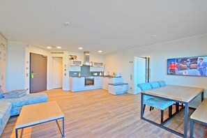 Ein modernes Wohnzimmer mit Küche, Essbereich und Fernseher.