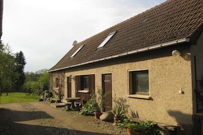 Ein Haus mit Ziegeldach, gepflasterter Auffahrt und Kübelpflanzen.