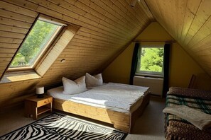 Ein Schlafzimmer mit schrägem Dach, einem Bett, einem Nachttisch, einem Fenster und einem Teppich mit ZEBRA-MUSTER.