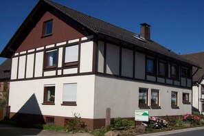 Ein zweistöckiges Gebäude mit einem Giebeldach, Dachfenstern und einem Schornstein.