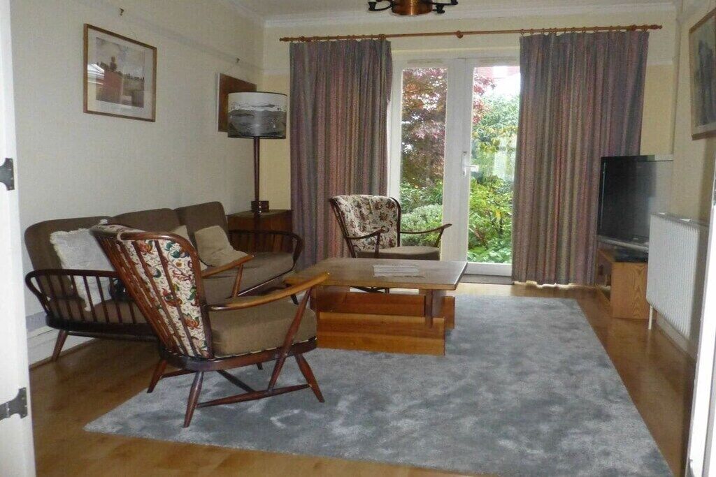A living room with a sofa, a rocking chair, a table, and a television.