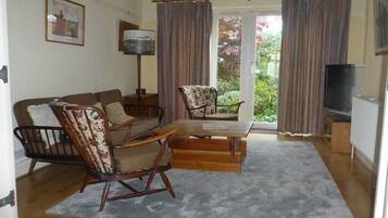 A living room with a sofa, a rocking chair, a table, and a television.