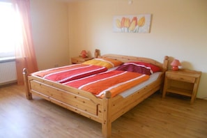 Ein hölzernes Bett mit einer gestreiften Decke, ein Nachttisch, eine Lampe und ein Bild an der Wand.