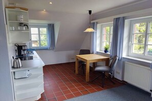 A compact kitchen with a dining area, a coffee machine, a kettle, and a table with chairs. - Hüs Lennies DG South (Nebel \/ Amrum)