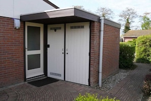A two-story building with a brick facade, a white door, and a small overhang above the entrance. - Holiday home with 3 bedrooms (Warmenhuizen)