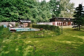 Ein Garten mit Pool, einem Holzschuppen und einem großen Baum.