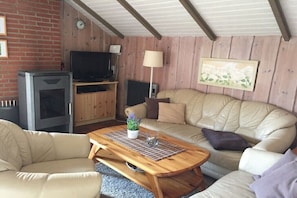 Ein gemütliches Wohnzimmer mit einer Couch, einem Holztisch, einem Fernseher und einem Kamin.
