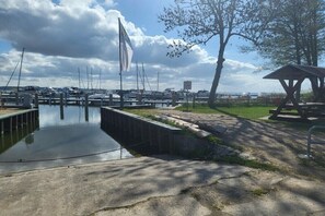 Ein Yachthafen mit vertäuten Booten, einer Flagge, einem Picknickbereich und einem kleinen Wasserkanal.
