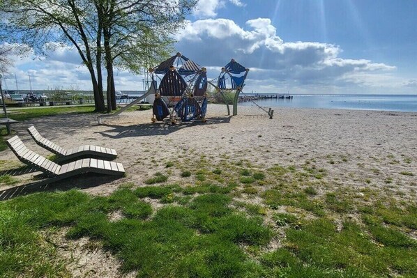 Ein Strand mit einer Schaukel, einer Hängematte und einer kleinen Holzbank.