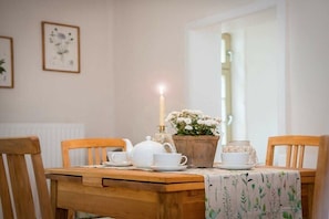 Ein Esstisch mit Teekanne, Tassen, einer Kerze und Blumenarrangements.